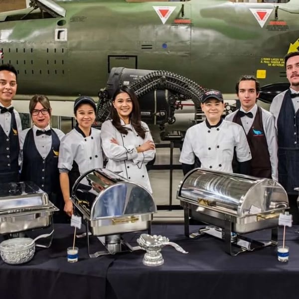Bangkok Garden staff, including chefs and servers, stand behind a buffet table with chafing dishes.