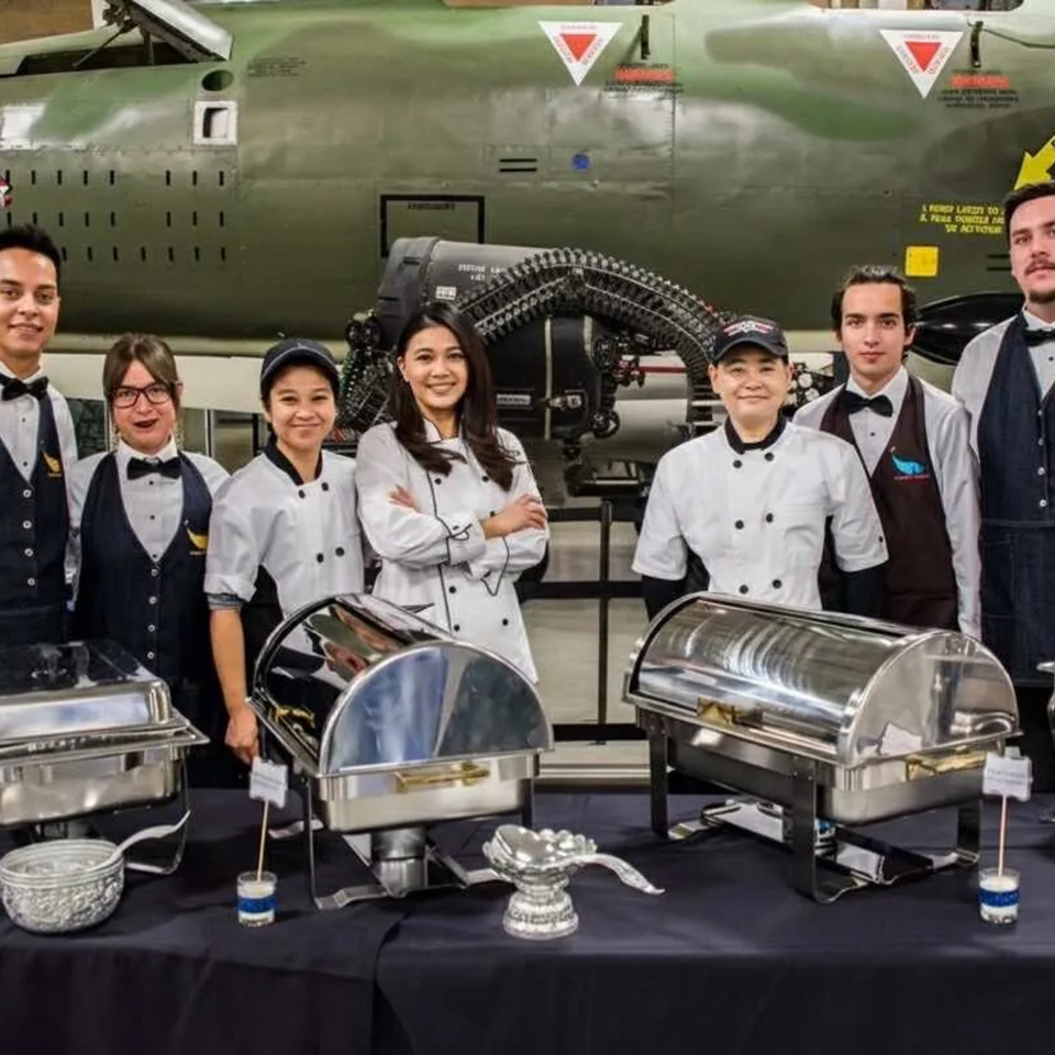 Bangkok Garden staff, including chefs and servers, stand behind a buffet table with chafing dishes.